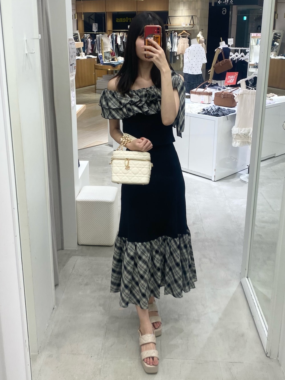 ブラック系のスカート、ホワイト系のショルダーバッグ、ベージュ系のサンダルを着用したレディースの秋コーディネートの3枚目の写真