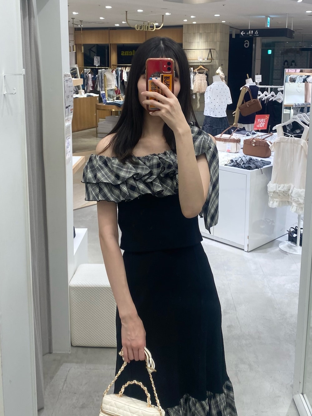 ブラック系のスカート、ホワイト系のショルダーバッグ、ベージュ系のサンダルを着用したレディースの秋コーディネートの2枚目の写真