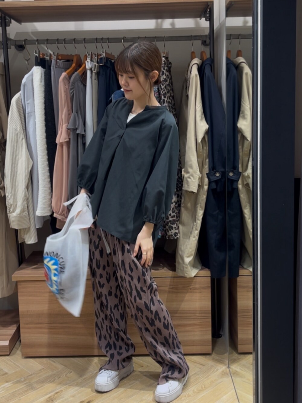 グレー系のシャツ/ブラウス、ホワイト系のハンドバッグ、ブラウン系のその他パンツを着用したレディースの春コーディネートの2枚目の写真