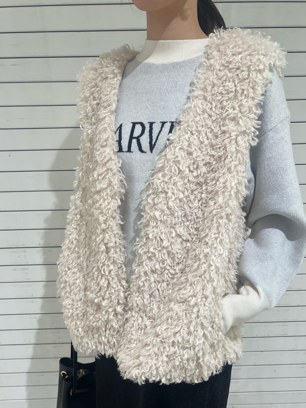 ブラック系のスカート、ホワイト系のベスト、シルバー系のその他シューズを着用したレディースの秋コーディネートの2枚目の写真