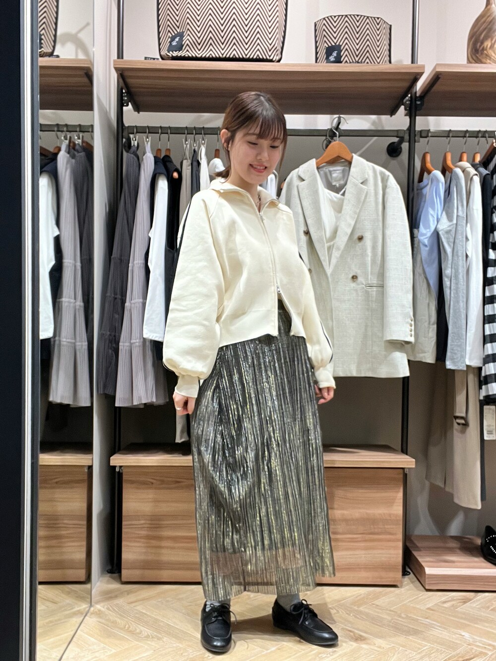 ホワイト系のニット/セーター、ブルー系のスカート、ブラック系のその他シューズを着用したレディースの春コーディネートの2枚目の写真