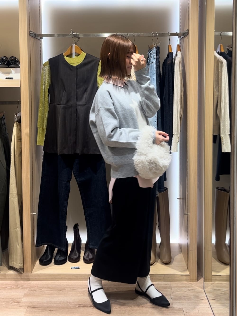 グレー系のニット/セーター、ブルー系のシャツ/ブラウス、ブラック系のスカートを着用したレディースの秋コーディネートの2枚目の写真