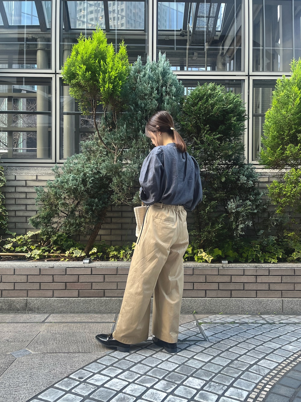 ホワイト系のハンドバッグ、ベージュ系のチノパンツ、グレー系のシャツ/ブラウスを着用したレディースの春コーディネートの2枚目の写真