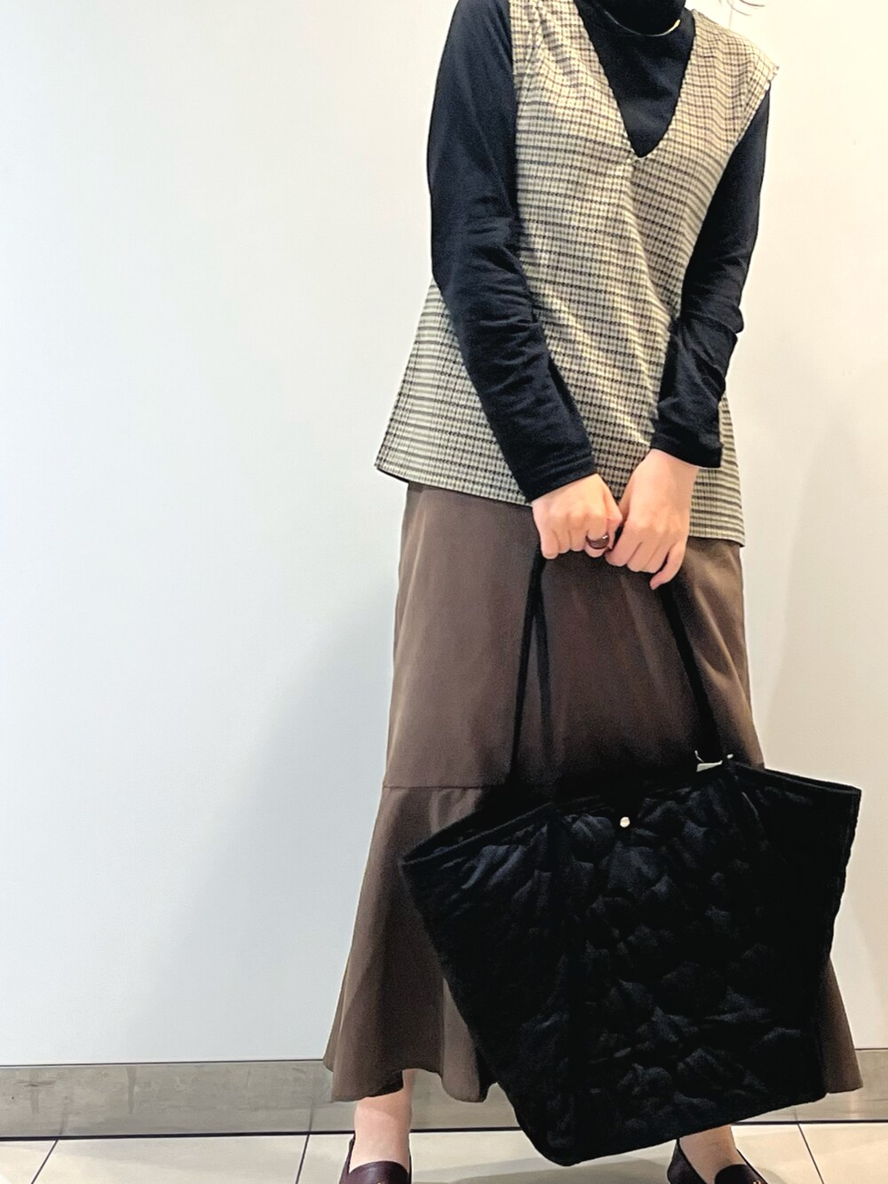 ブラック系のニット/セーター、ベージュ系のニット/セーター、ブラウン系のスカートを着用したレディースの秋コーディネートの2枚目の写真