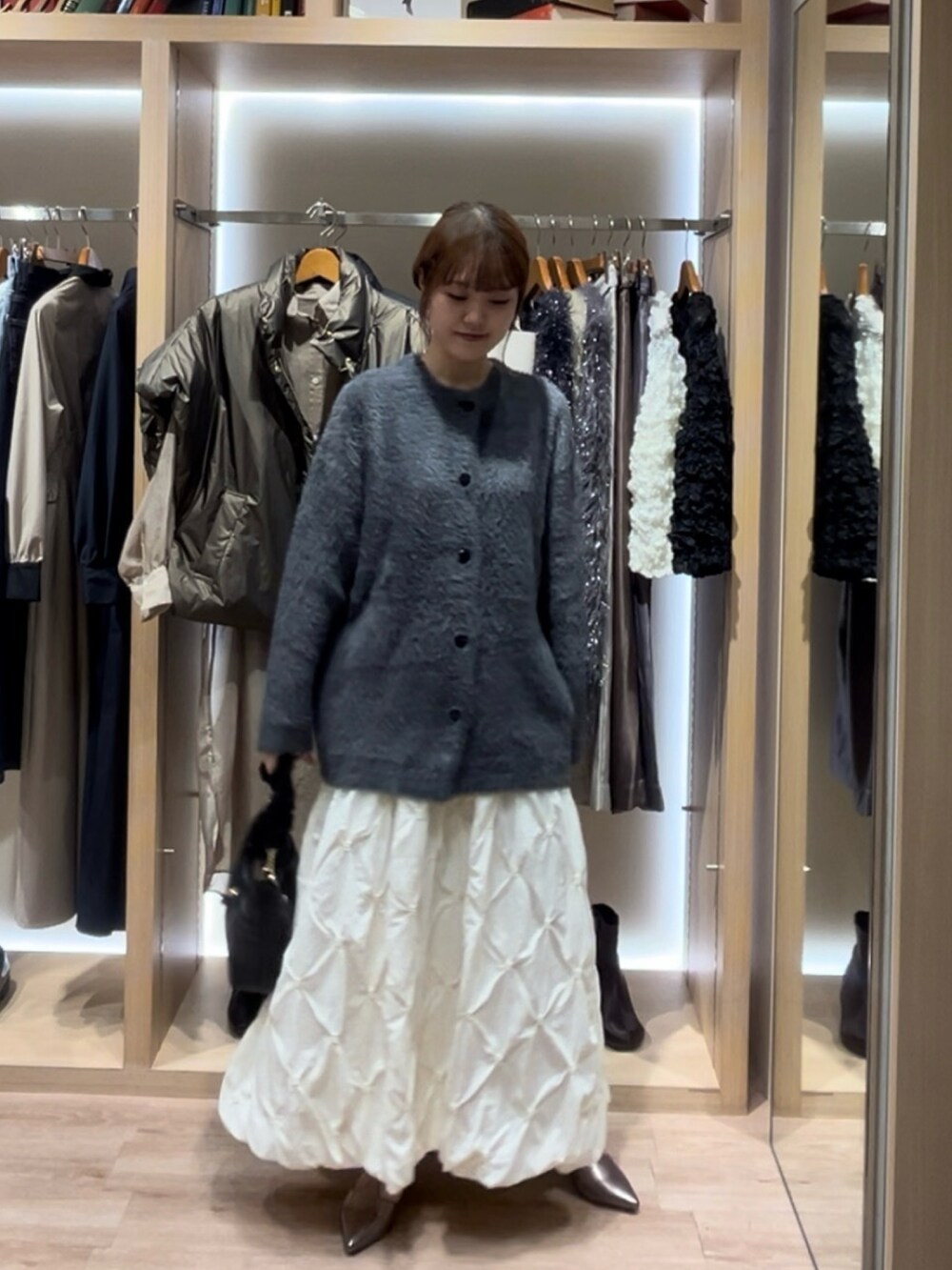 グレー系のカーディガン/ボレロ、ブラック系のスカート、ホワイト系のスカートを着用したレディースの秋コーディネートの2枚目の写真