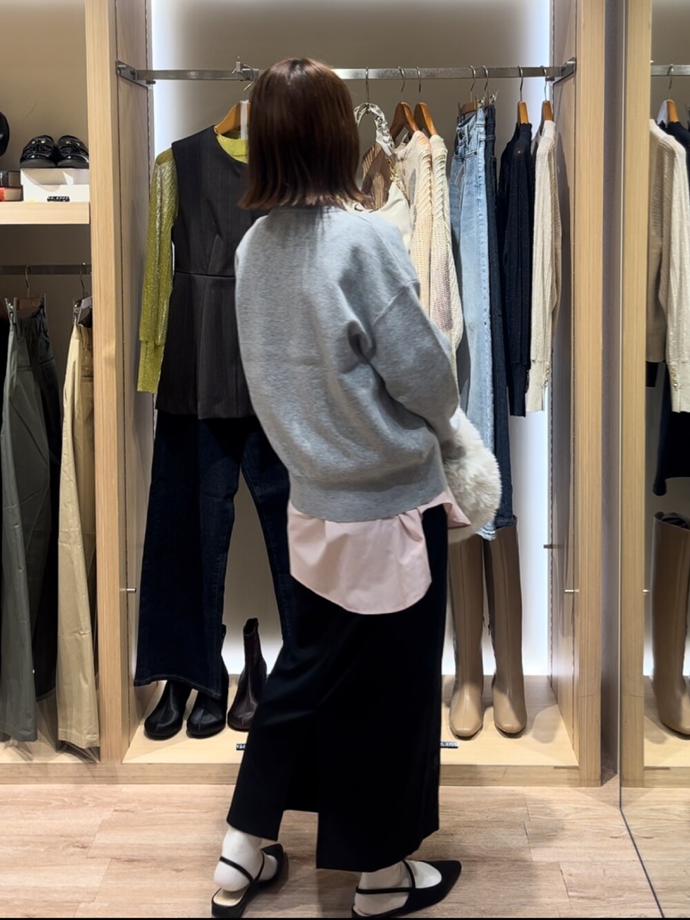 グレー系のニット/セーター、ブルー系のシャツ/ブラウス、ブラック系のスカートを着用したレディースの秋コーディネートの3枚目の写真