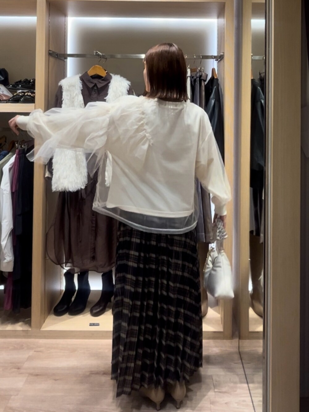 ホワイト系のTシャツ/カットソー、ブルー系のスカート、ホワイト系のハンドバッグを着用したレディースの秋コーディネートの3枚目の写真