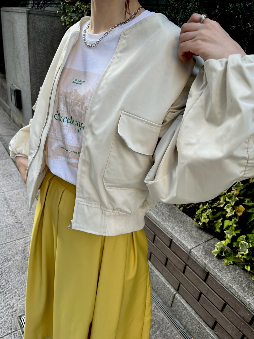 イエロー系のスカート、ブラック系のローファー、ホワイト系のブルゾンを着用したレディースの春コーディネートの2枚目の写真