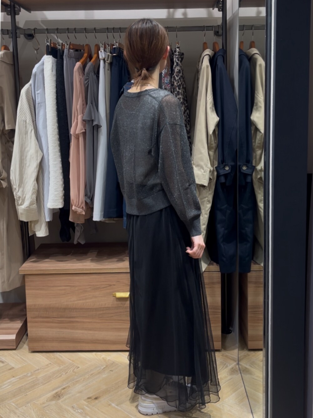 グレー系のカーディガン/ボレロ、ブラック系のスカート、ホワイト系のタンクトップを着用したレディースの春コーディネートの2枚目の写真