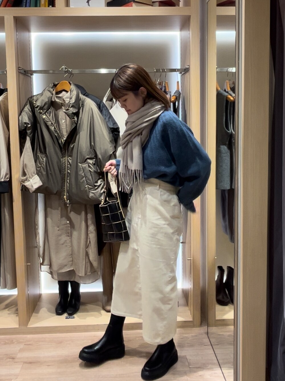 ブルー系のニット/セーター、ブラック系のハンドバッグ、ブラック系のブーツを着用したレディースの秋コーディネートの2枚目の写真