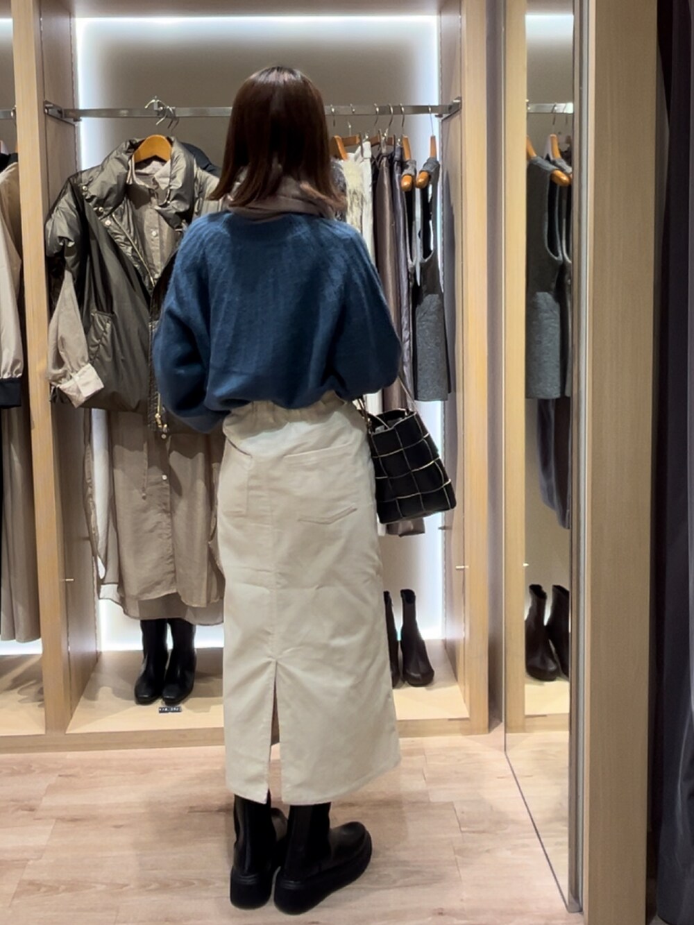 ブルー系のニット/セーター、ブラック系のハンドバッグ、ブラック系のブーツを着用したレディースの秋コーディネートの3枚目の写真