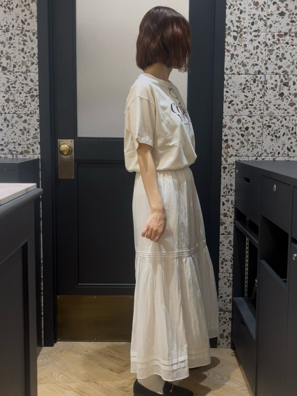 ホワイト系のTシャツ/カットソー、ホワイト系のスカート、ブラック系のその他シューズを着用したレディースの春コーディネートの2枚目の写真