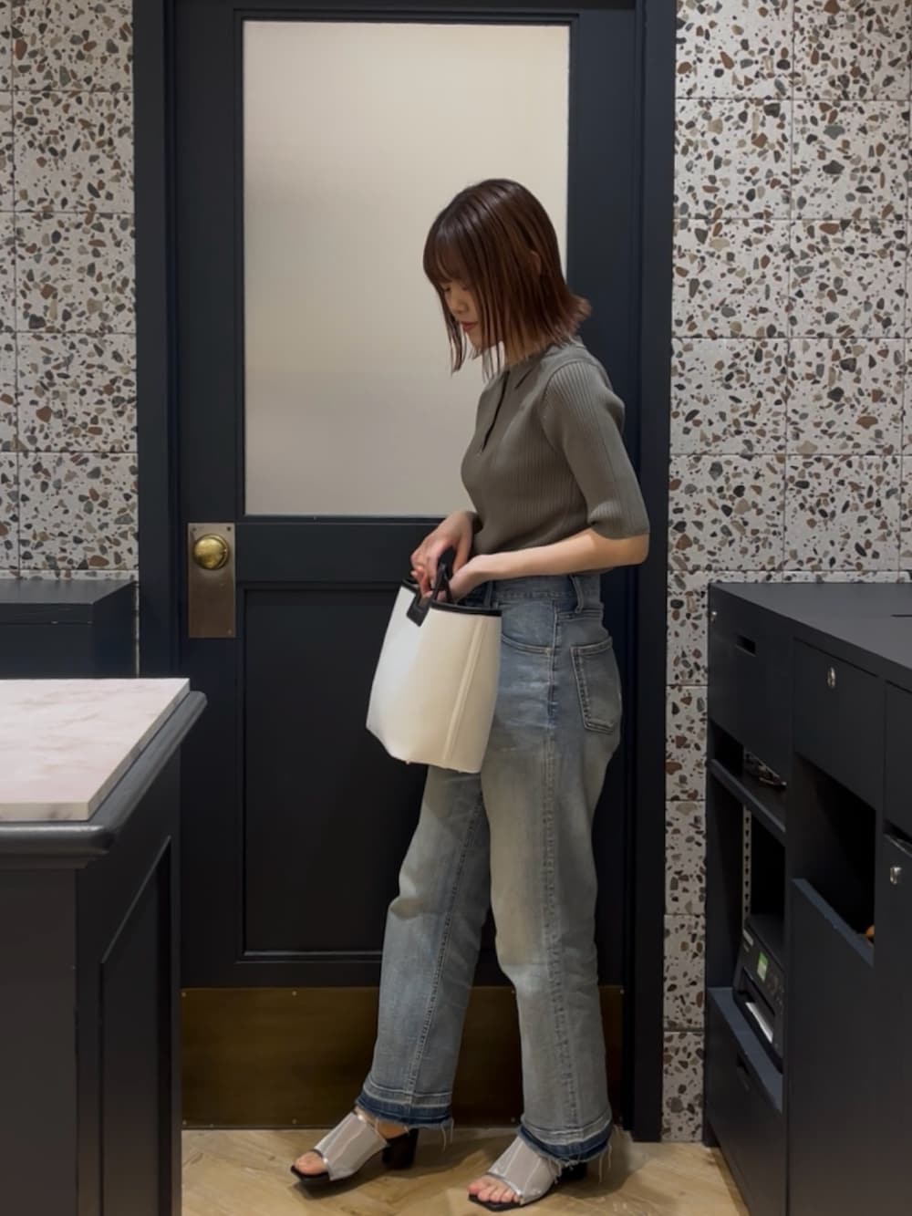 グリーン系のニット/セーター、ブルー系のその他パンツ、ホワイト系のハンドバッグを着用したレディースの春コーディネートの2枚目の写真