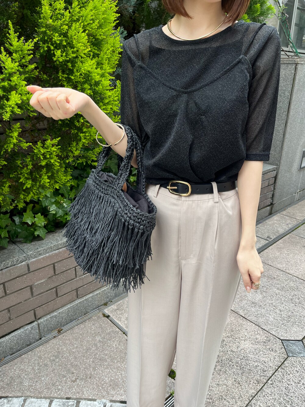 ブラック系のTシャツ/カットソー、ブラック系のハンドバッグ、ベージュ系のスラックスを着用したレディースの春コーディネートの3枚目の写真