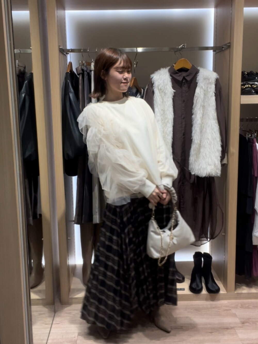 ホワイト系のTシャツ/カットソー、ブルー系のスカート、ホワイト系のハンドバッグを着用したレディースの秋コーディネートの2枚目の写真