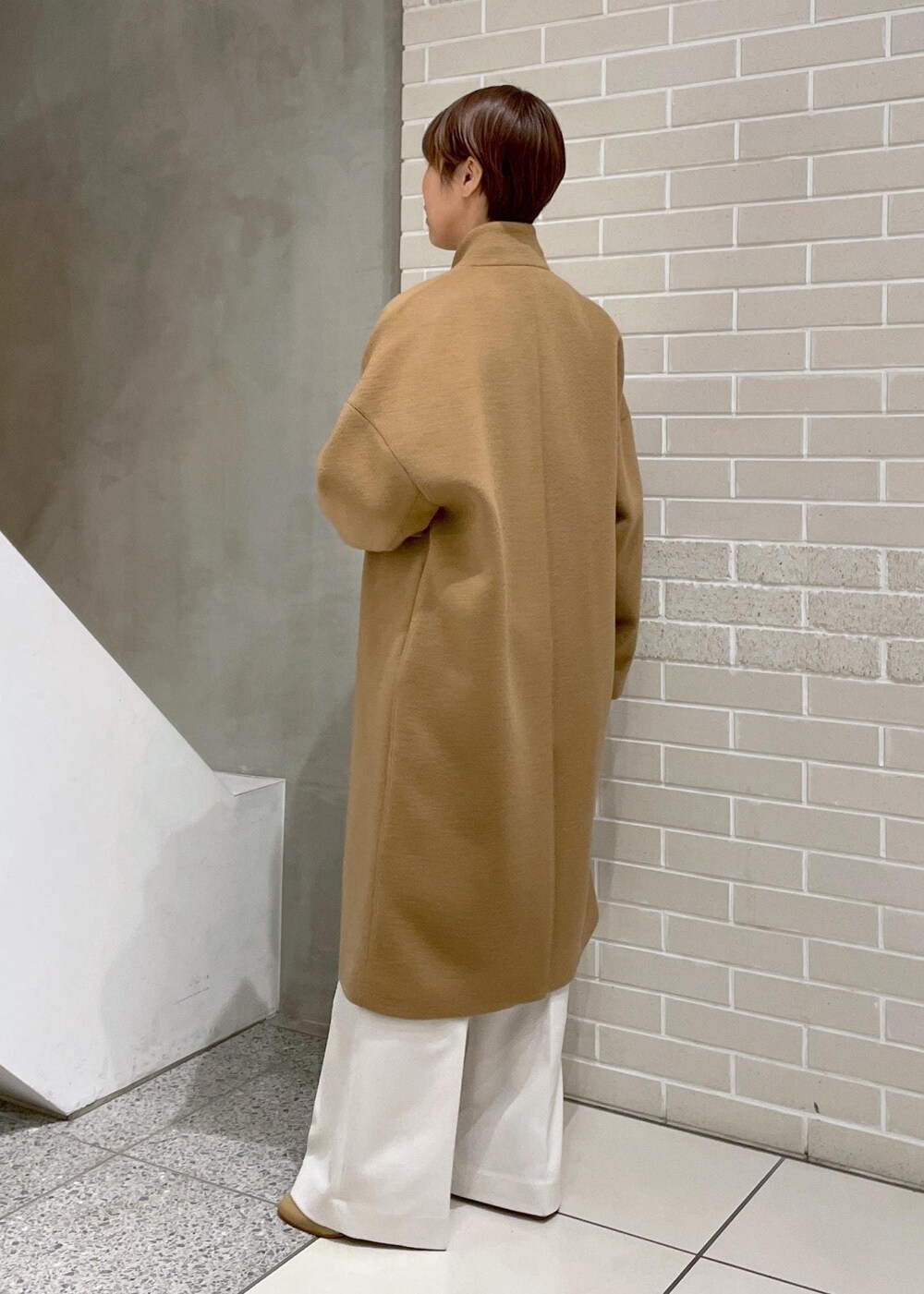 イエロー系のチェスターコート、ホワイト系のその他パンツ、ホワイト系のカーディガン/ボレロを着用したレディースの冬コーディネートの5枚目の写真