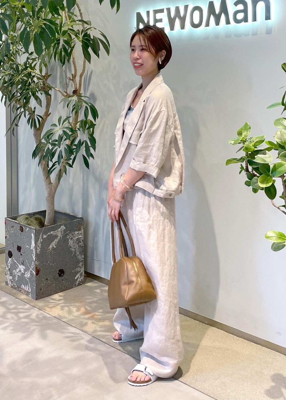 ブラウン系のボストンバッグ、ホワイト系のサンダル、ベージュ系のブルゾンを着用したレディースの夏コーディネートの3枚目の写真