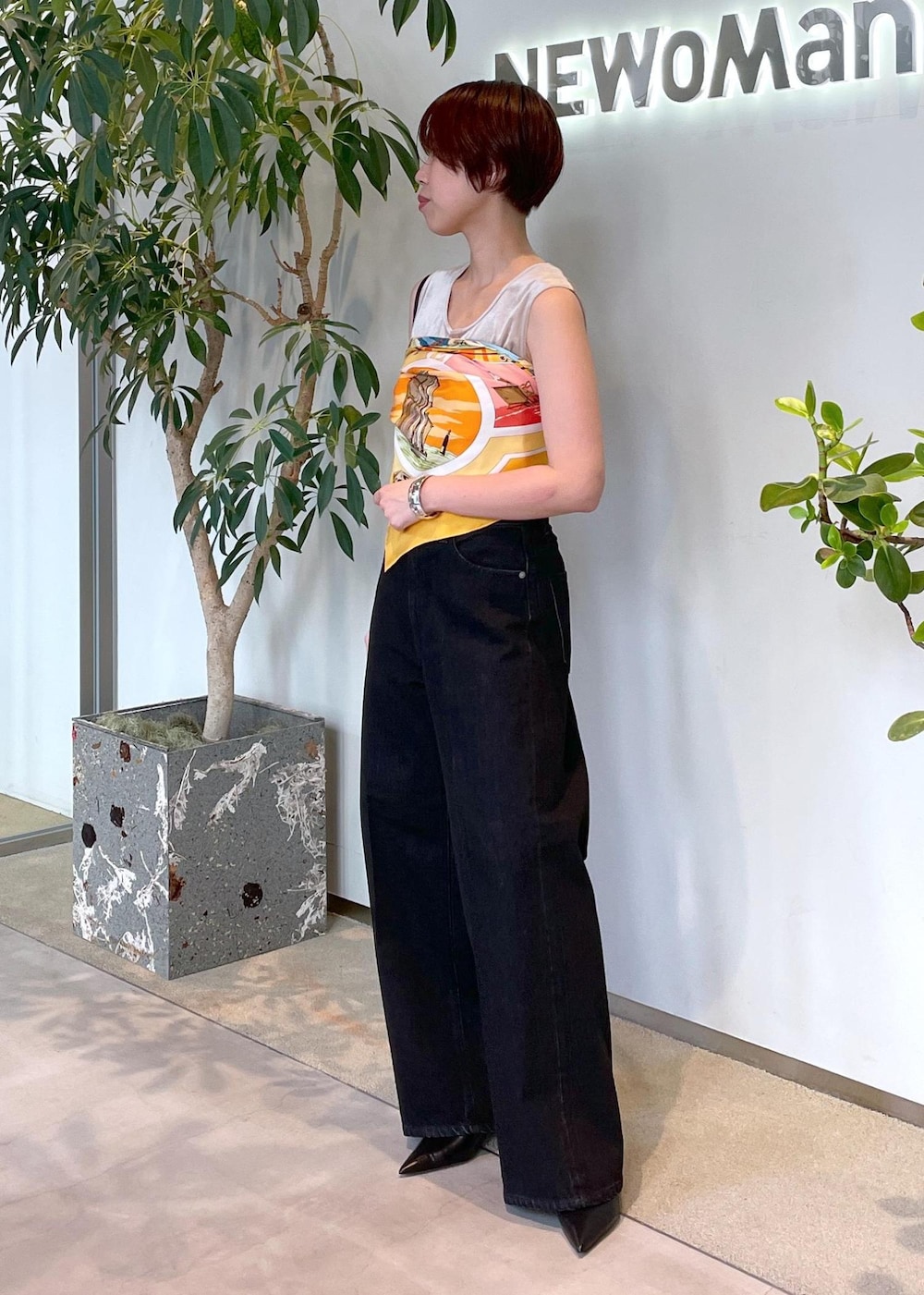 ベージュ系のタンクトップ、グレー系のデニムパンツ、ブラック系のパンプスを着用したレディースの夏コーディネートの4枚目の写真