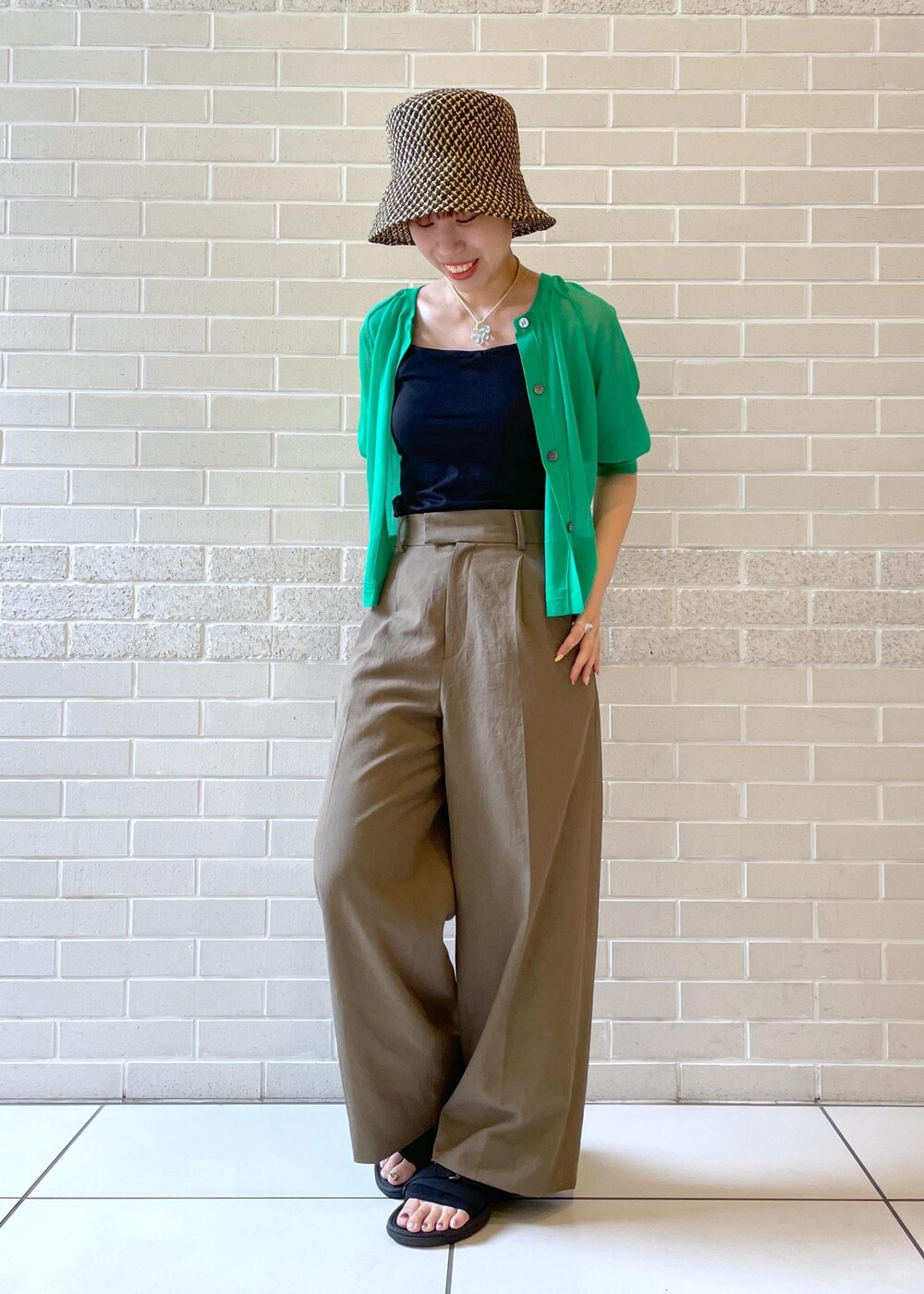 ブラウン系のその他パンツ、グリーン系のカーディガン/ボレロ、ブラック系のハットを着用したレディースの春コーディネートの2枚目の写真