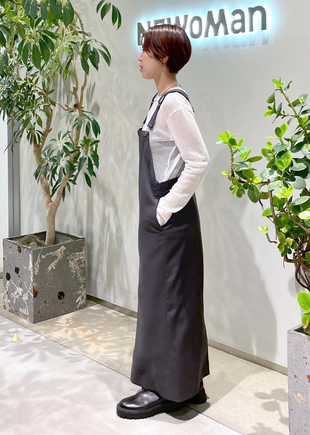 ブラック系のブーツ、グレー系のジャンパースカート、ブラウン系のショルダーバッグを着用したレディースの秋コーディネートの3枚目の写真