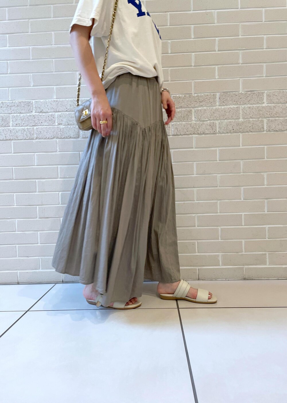 ホワイト系のTシャツ/カットソー、ベージュ系のサンダル、グレー系のスカートを着用したレディースの春コーディネートの6枚目の写真