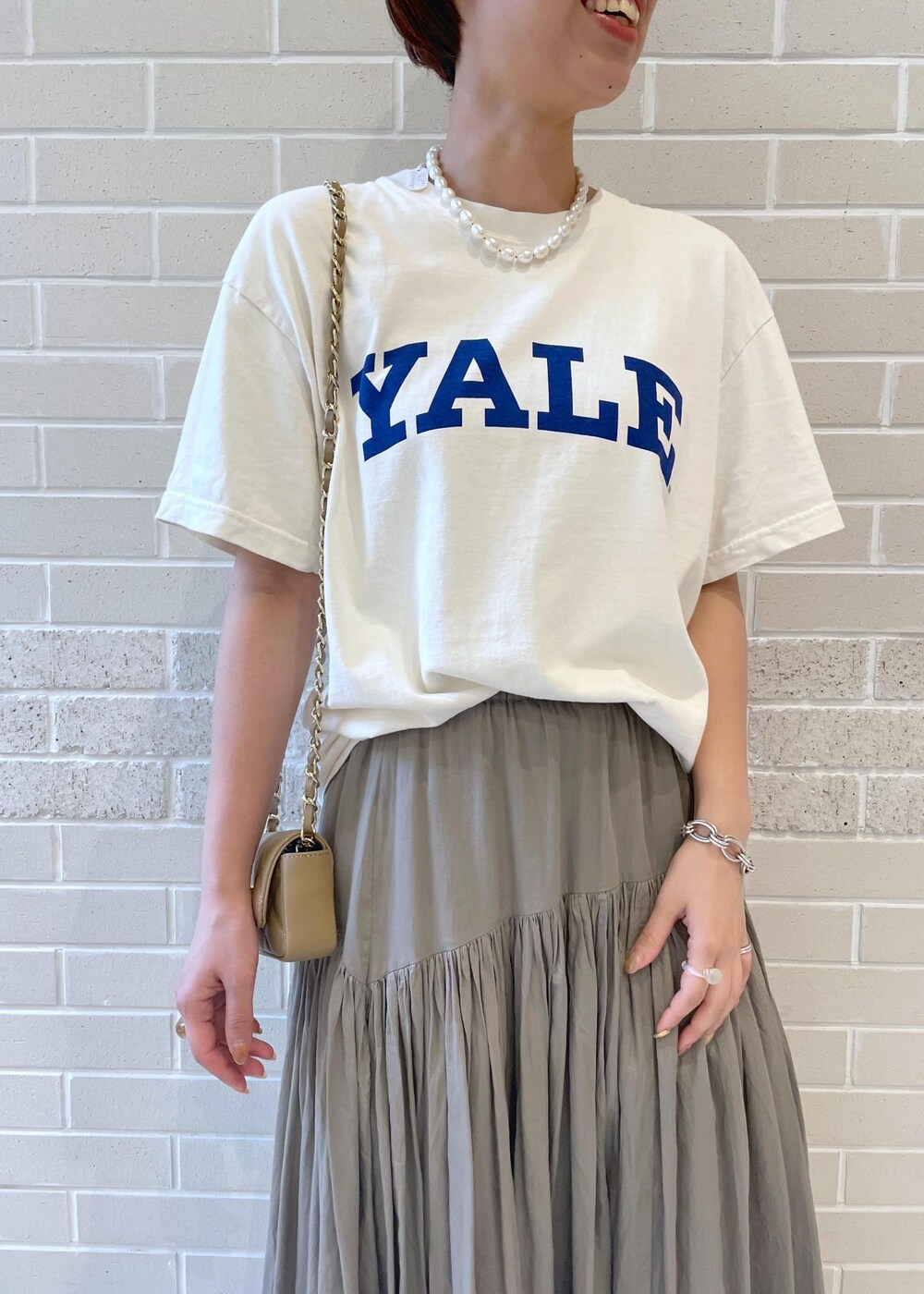 ホワイト系のTシャツ/カットソー、ベージュ系のサンダル、グレー系のスカートを着用したレディースの春コーディネートの4枚目の写真