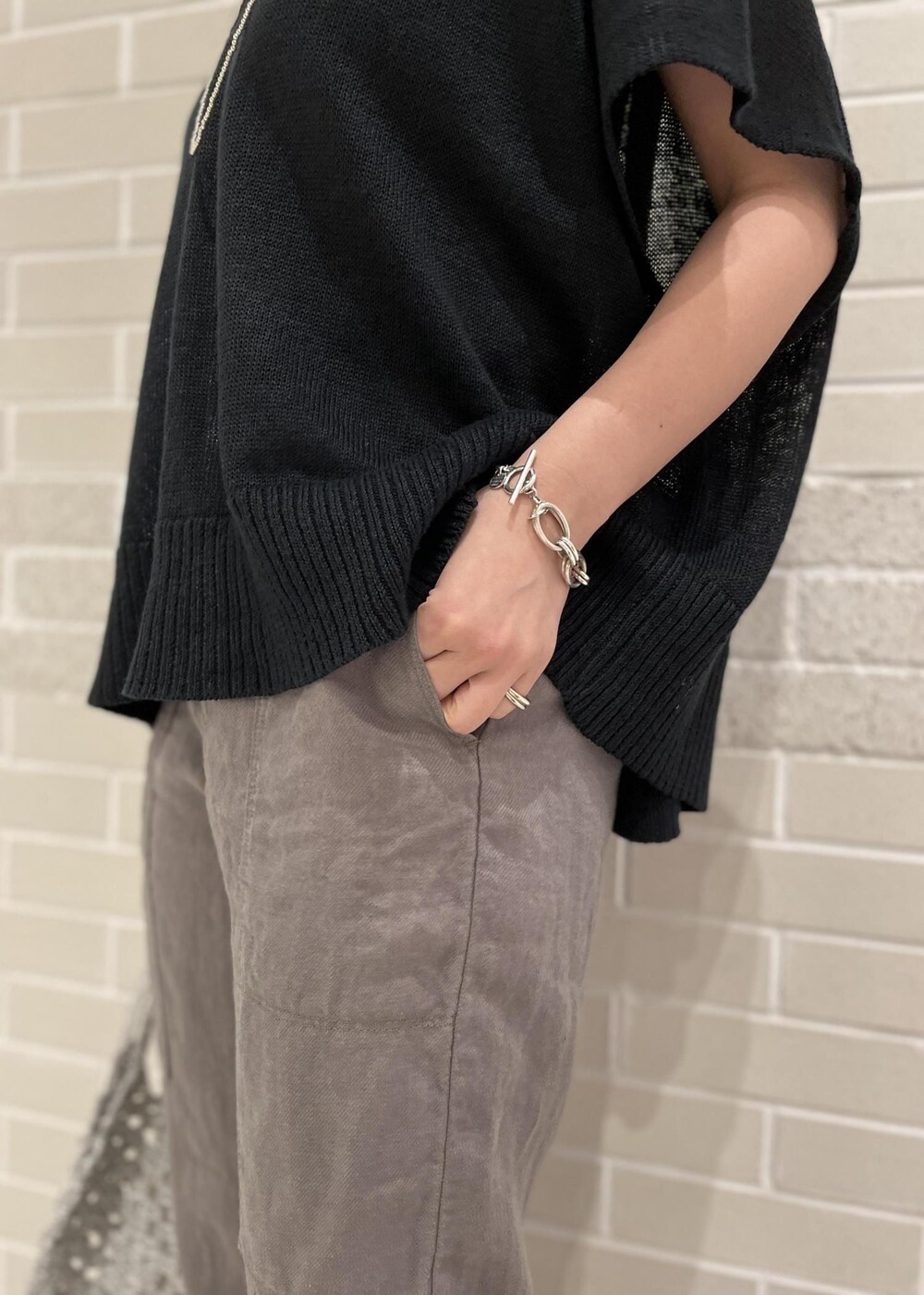 ブラック系のサンダル、ホワイト系のハンドバッグ、ブラック系のニット/セーターを着用したレディースの春コーディネートの6枚目の写真