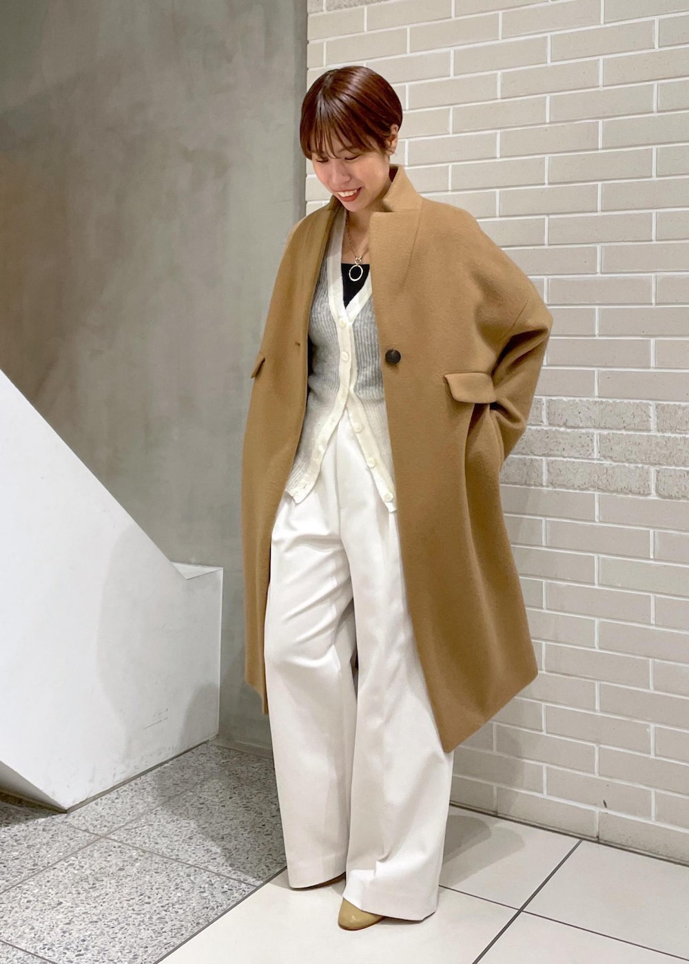 イエロー系のチェスターコート、ホワイト系のその他パンツ、ホワイト系のカーディガン/ボレロを着用したレディースの冬コーディネートの3枚目の写真