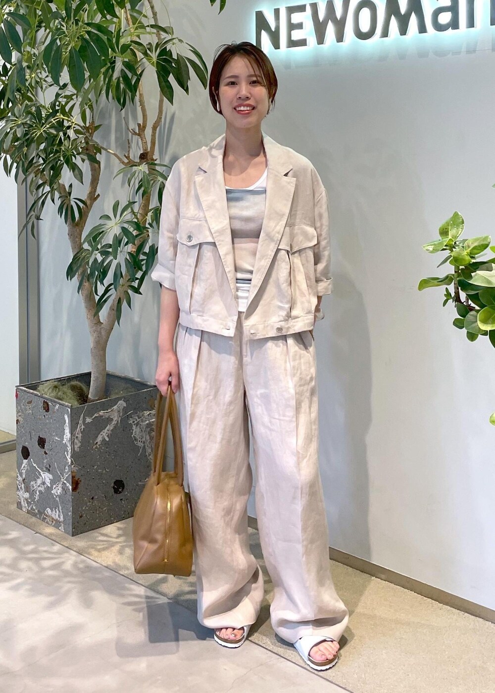 ブラウン系のボストンバッグ、ホワイト系のサンダル、ベージュ系のブルゾンを着用したレディースの夏コーディネートの2枚目の写真
