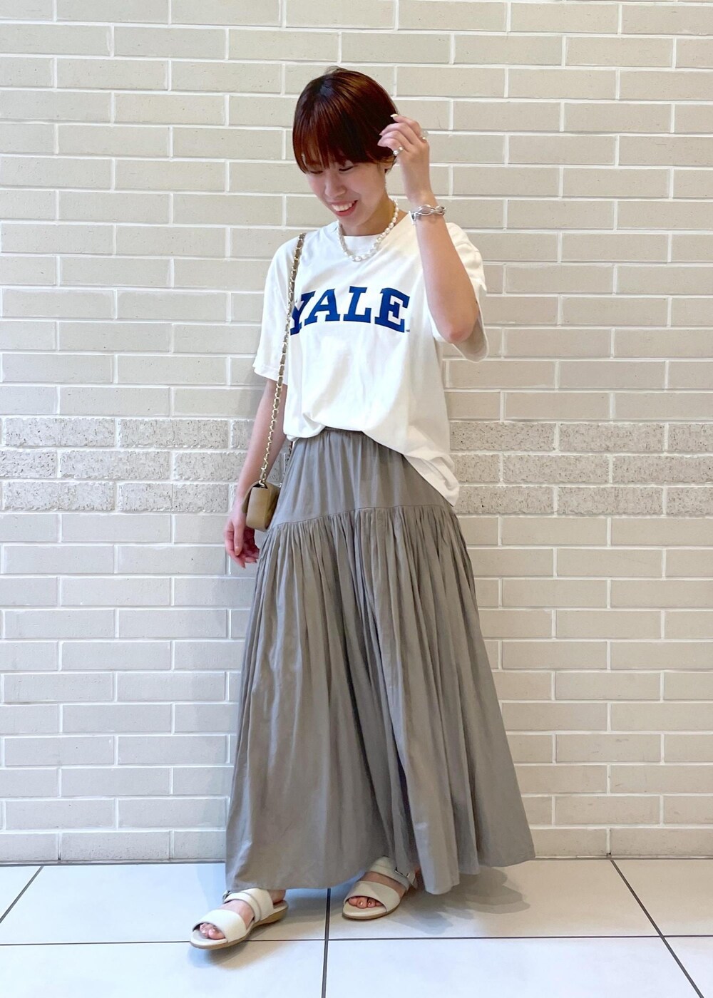 ホワイト系のTシャツ/カットソー、ベージュ系のサンダル、グレー系のスカートを着用したレディースの春コーディネートの3枚目の写真