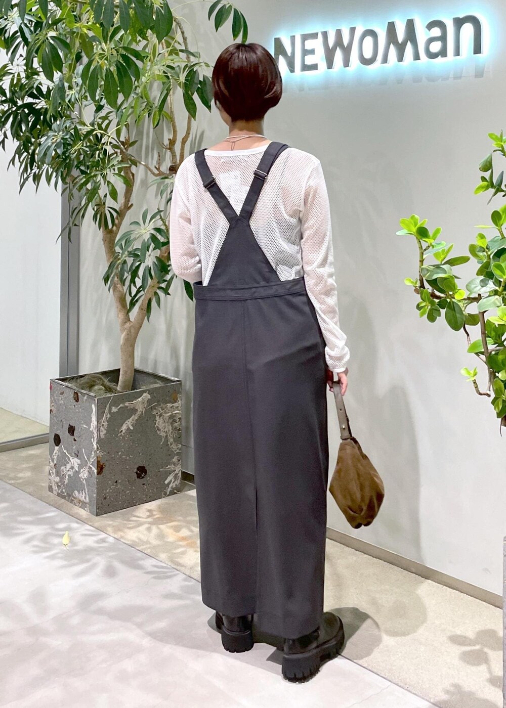 ブラック系のブーツ、グレー系のジャンパースカート、ブラウン系のショルダーバッグを着用したレディースの秋コーディネートの4枚目の写真