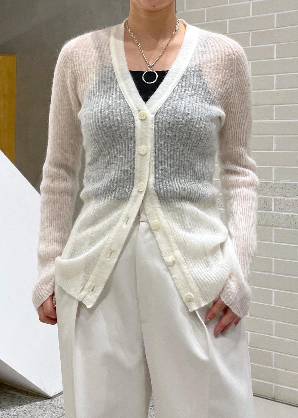 イエロー系のチェスターコート、ホワイト系のその他パンツ、ホワイト系のカーディガン/ボレロを着用したレディースの冬コーディネートの7枚目の写真