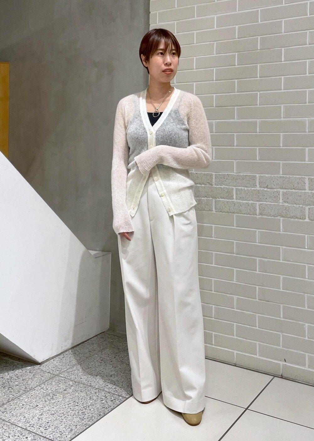 イエロー系のチェスターコート、ホワイト系のその他パンツ、ホワイト系のカーディガン/ボレロを着用したレディースの冬コーディネートの6枚目の写真