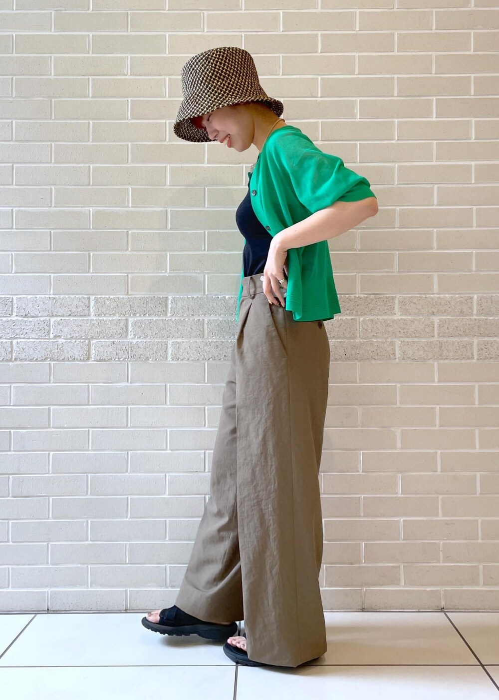 ブラウン系のその他パンツ、グリーン系のカーディガン/ボレロ、ブラック系のハットを着用したレディースの春コーディネートの3枚目の写真