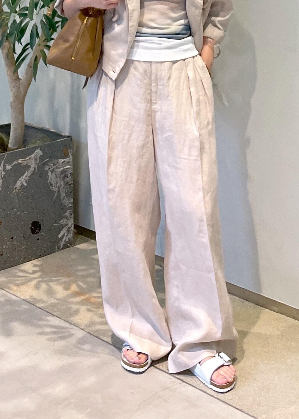 ブラウン系のボストンバッグ、ホワイト系のサンダル、ベージュ系のブルゾンを着用したレディースの夏コーディネートの7枚目の写真