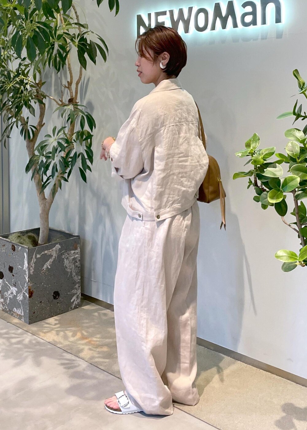 ブラウン系のボストンバッグ、ホワイト系のサンダル、ベージュ系のブルゾンを着用したレディースの夏コーディネートの4枚目の写真