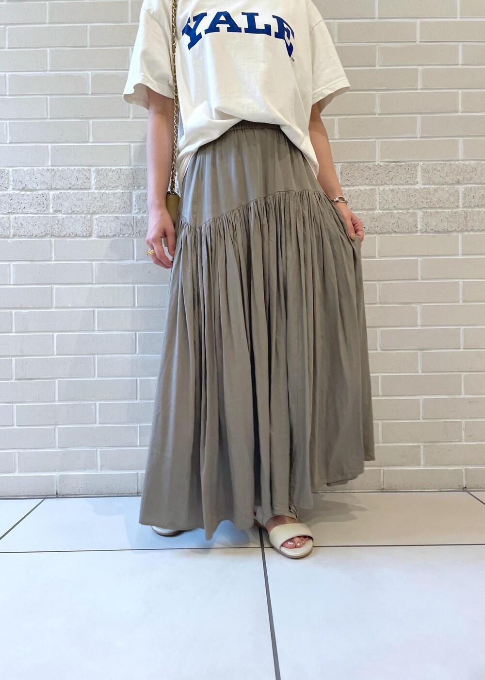 ホワイト系のTシャツ/カットソー、ベージュ系のサンダル、グレー系のスカートを着用したレディースの春コーディネートの5枚目の写真