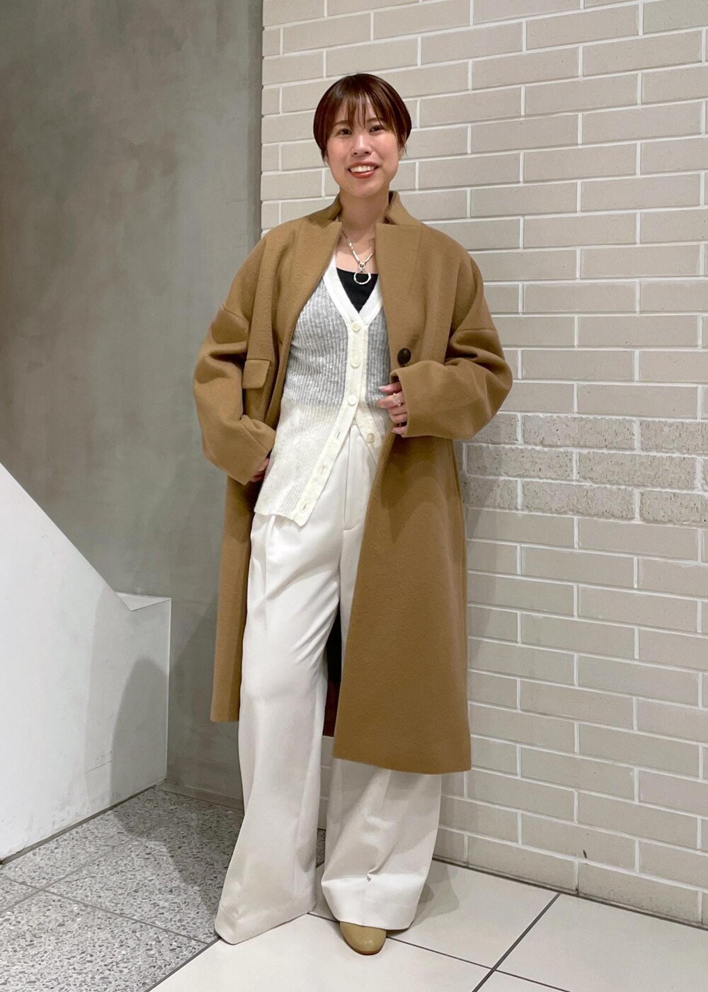 イエロー系のチェスターコート、ホワイト系のその他パンツ、ホワイト系のカーディガン/ボレロを着用したレディースの冬コーディネートの2枚目の写真