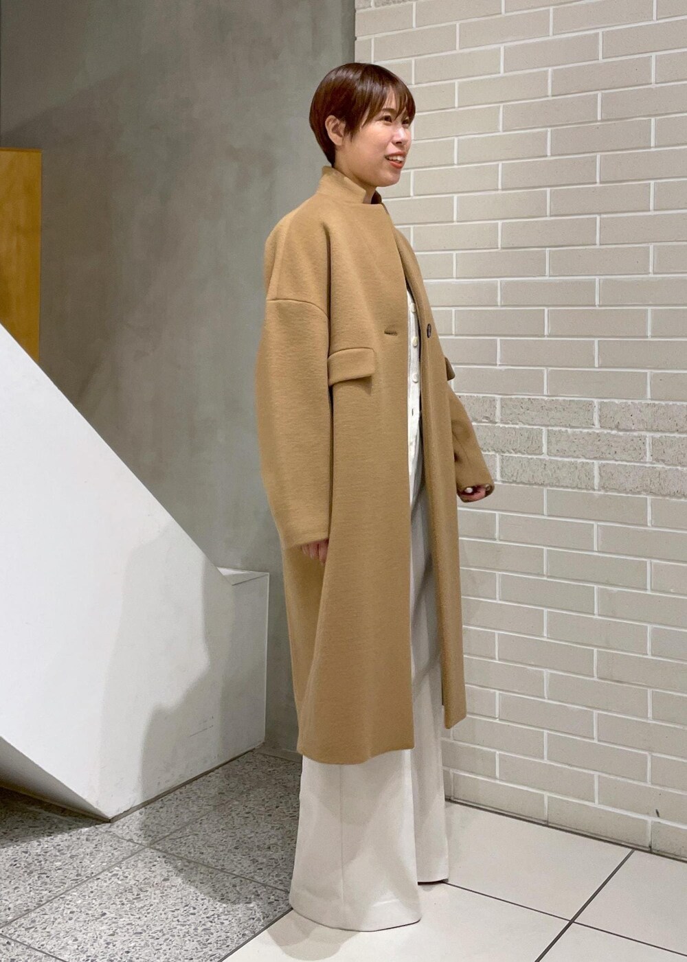 イエロー系のチェスターコート、ホワイト系のその他パンツ、ホワイト系のカーディガン/ボレロを着用したレディースの冬コーディネートの4枚目の写真