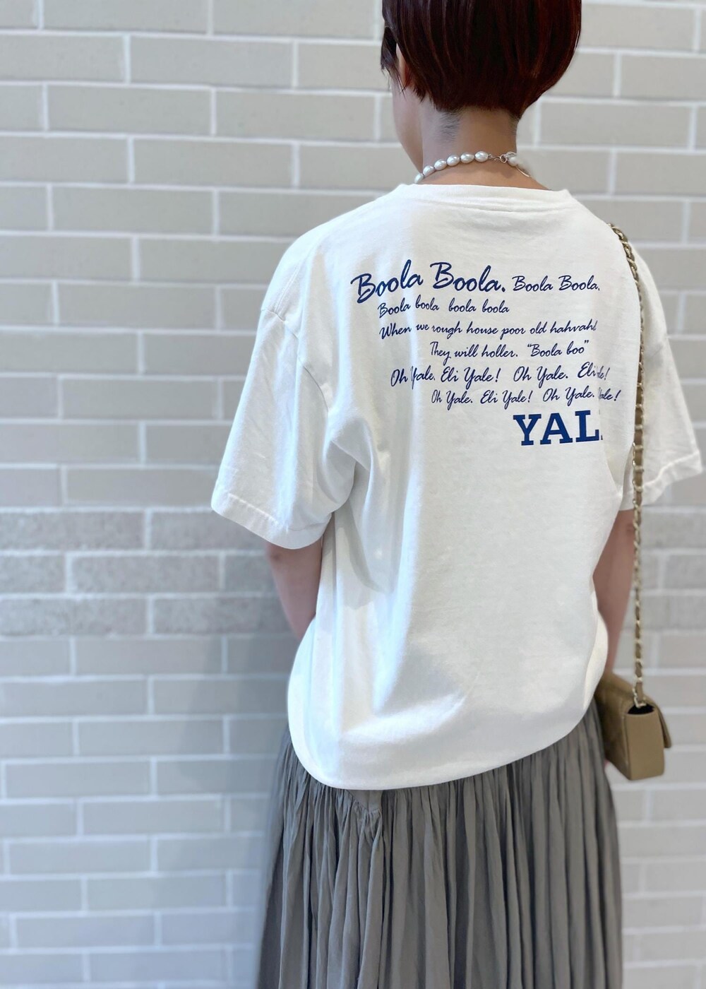 ホワイト系のTシャツ/カットソー、ベージュ系のサンダル、グレー系のスカートを着用したレディースの春コーディネートの7枚目の写真