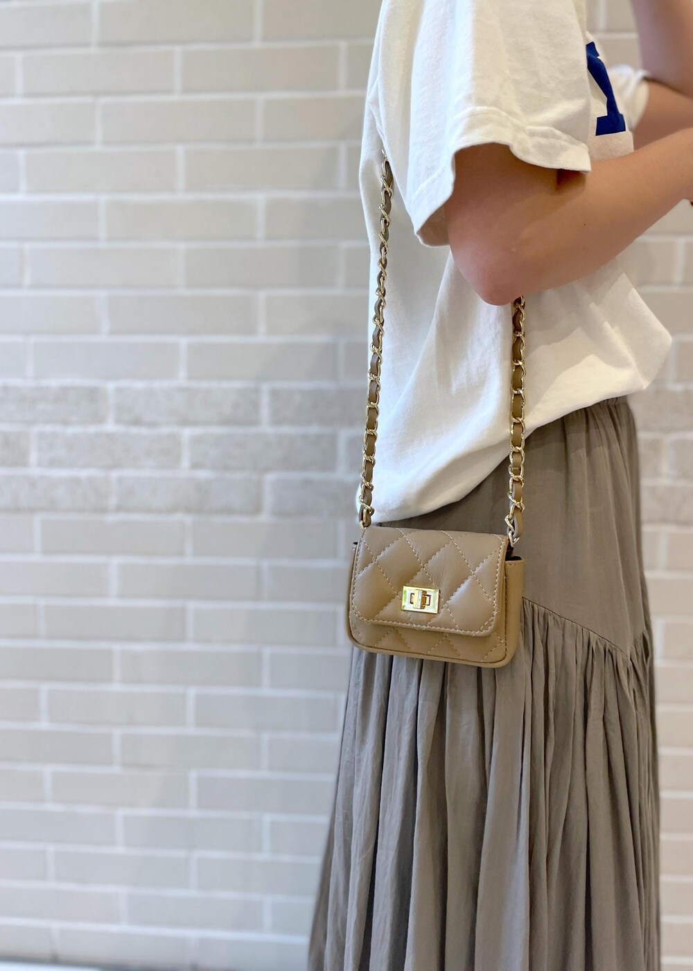 ホワイト系のTシャツ/カットソー、ベージュ系のサンダル、グレー系のスカートを着用したレディースの春コーディネートの8枚目の写真