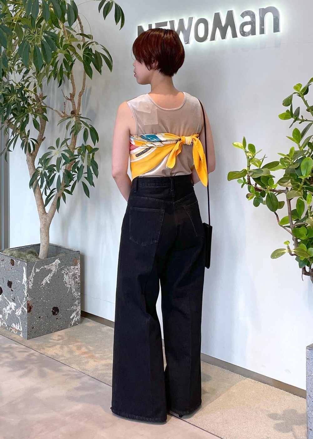 ベージュ系のタンクトップ、グレー系のデニムパンツ、ブラック系のパンプスを着用したレディースの夏コーディネートの3枚目の写真