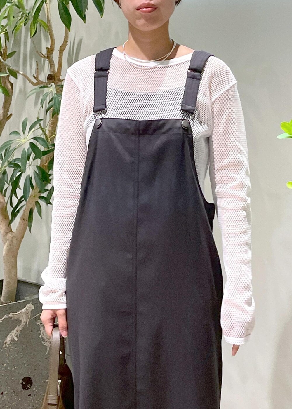 ブラック系のブーツ、グレー系のジャンパースカート、ブラウン系のショルダーバッグを着用したレディースの秋コーディネートの5枚目の写真