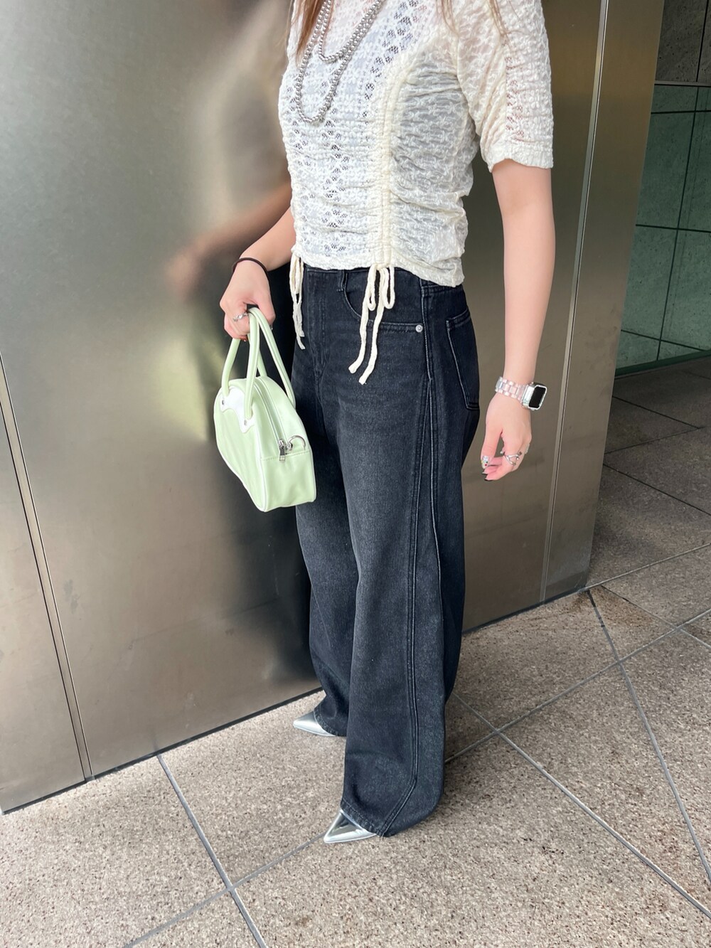 ブラック系のデニムパンツ、グリーン系のトートバッグ、ホワイト系のTシャツ/カットソーを着用したレディースの夏コーディネートの3枚目の写真