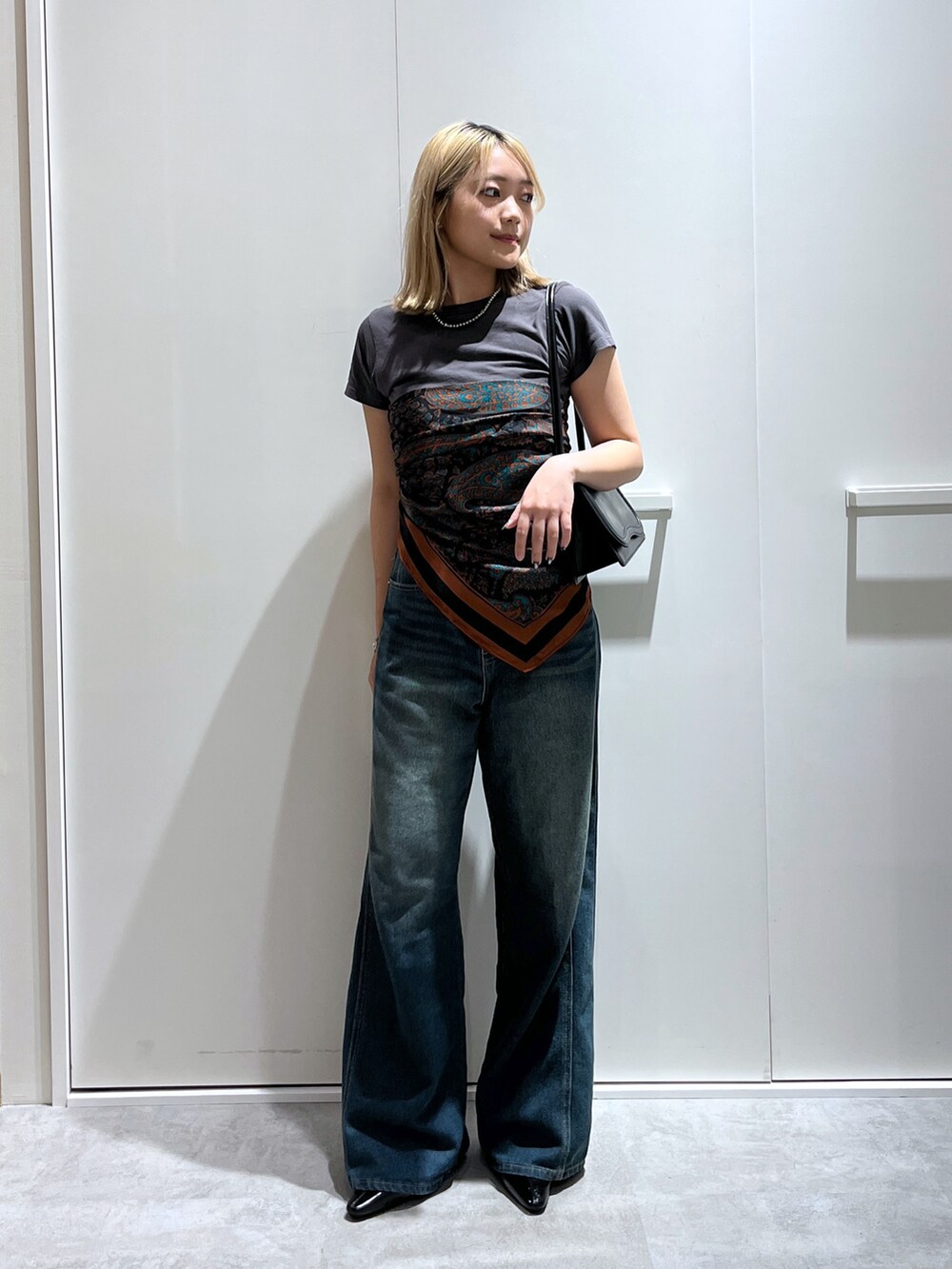 グレー系のTシャツ/カットソー、ブルー系のデニムパンツ、ブラック系のショルダーバッグを着用したレディースの秋コーディネートの2枚目の写真