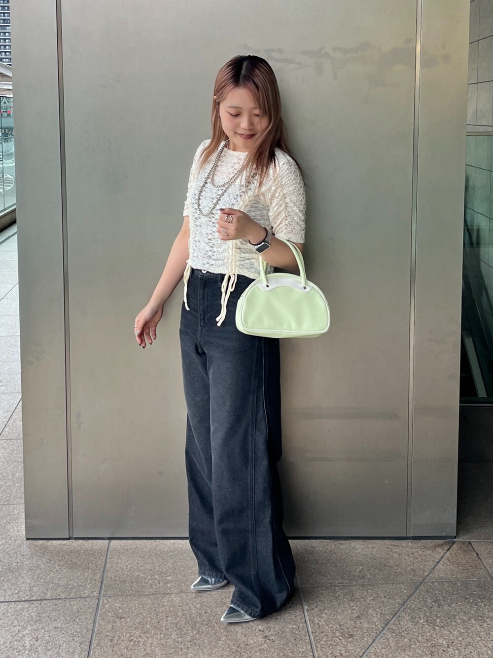 ブラック系のデニムパンツ、グリーン系のトートバッグ、ホワイト系のTシャツ/カットソーを着用したレディースの夏コーディネートの2枚目の写真