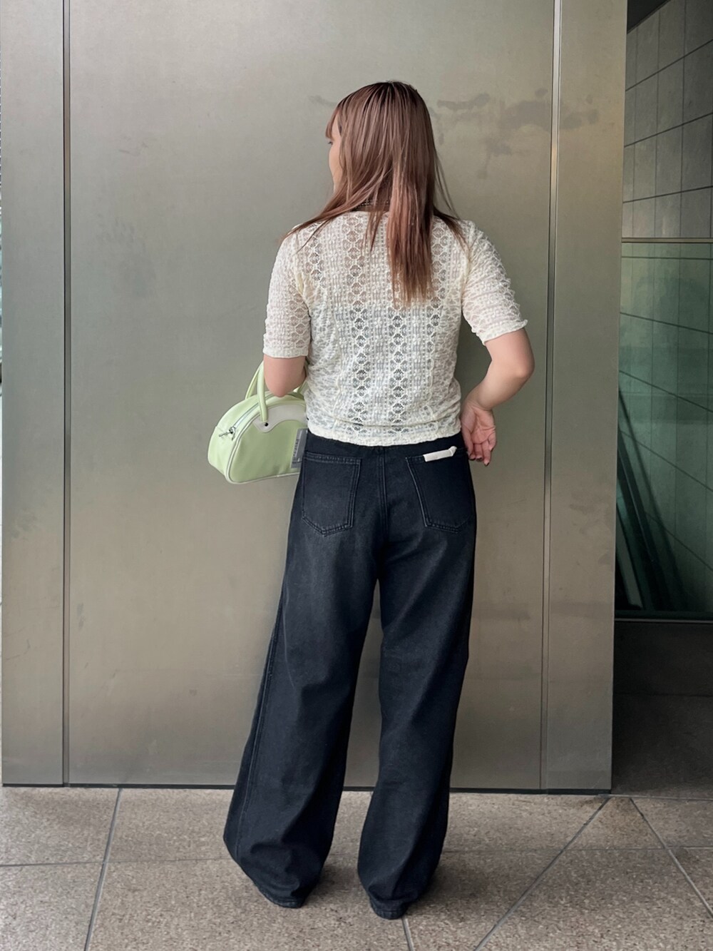 ブラック系のデニムパンツ、グリーン系のトートバッグ、ホワイト系のTシャツ/カットソーを着用したレディースの夏コーディネートの4枚目の写真