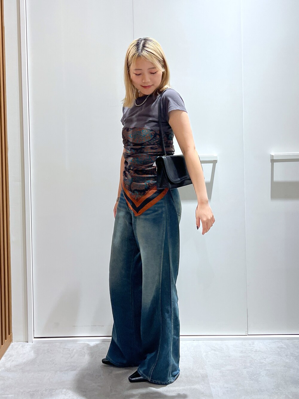 グレー系のTシャツ/カットソー、ブルー系のデニムパンツ、ブラック系のショルダーバッグを着用したレディースの秋コーディネートの4枚目の写真