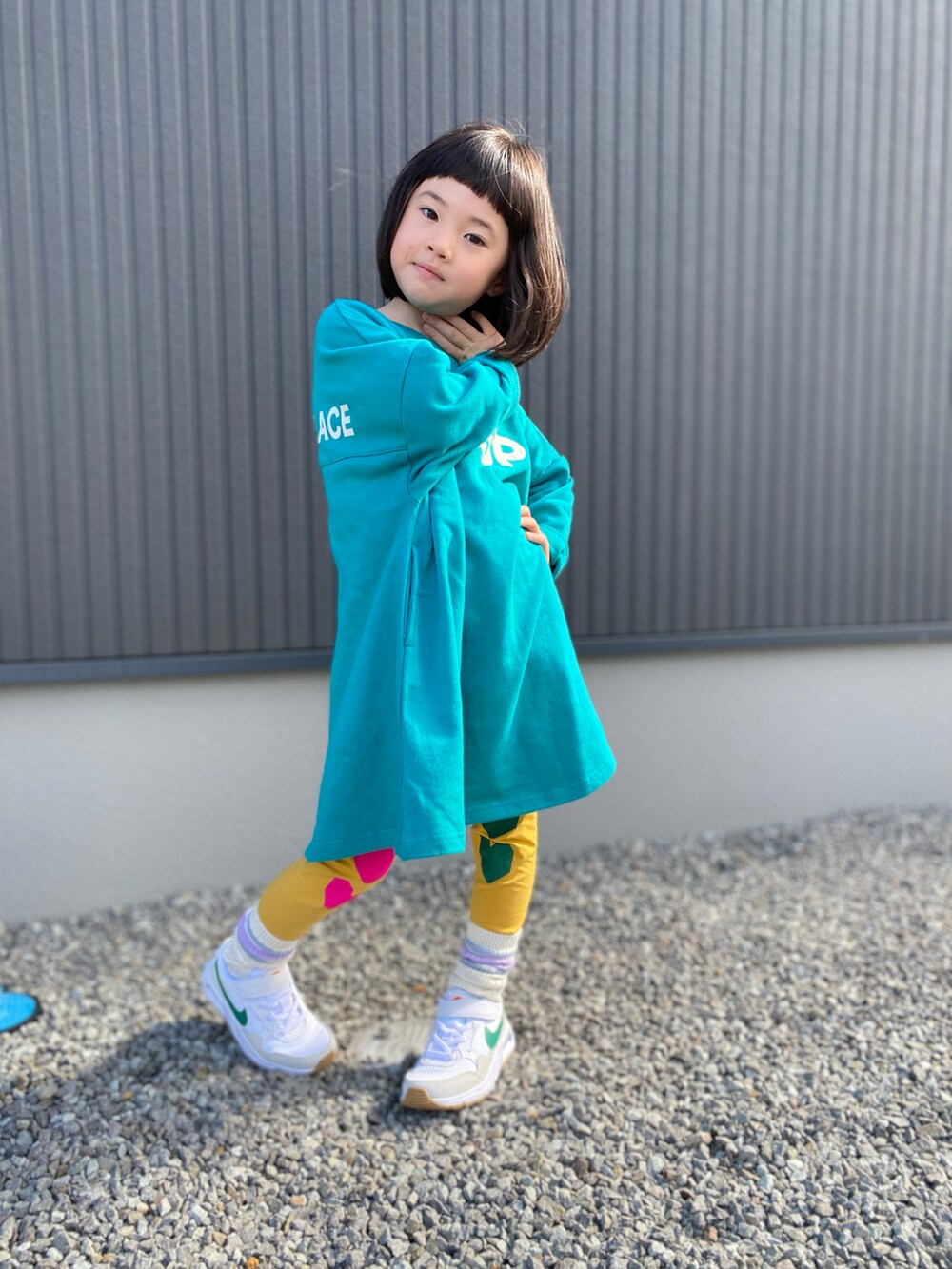 グリーン系のワンピース、ホワイト系のスニーカー、イエロー系のレギンス/スパッツを着用したキッズの春コーディネートの2枚目の写真