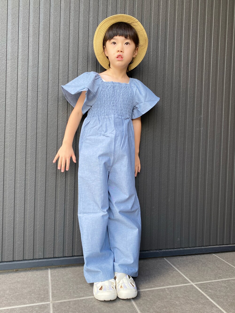 ブルー系のサロペット/オーバーオール、ホワイト系のサンダル、ベージュ系のハットを着用したキッズの夏コーディネートの2枚目の写真